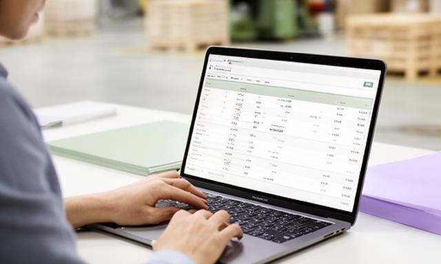 Procurement specialist reviewing bulk pricing on a laptop in a bright warehouse office